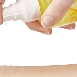 Person sprüht sich CAPITAL SOLEIL Sonnenspray auf den Arm