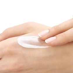 Person verteilt ein wenig milchige Creme auf ihrer Hand