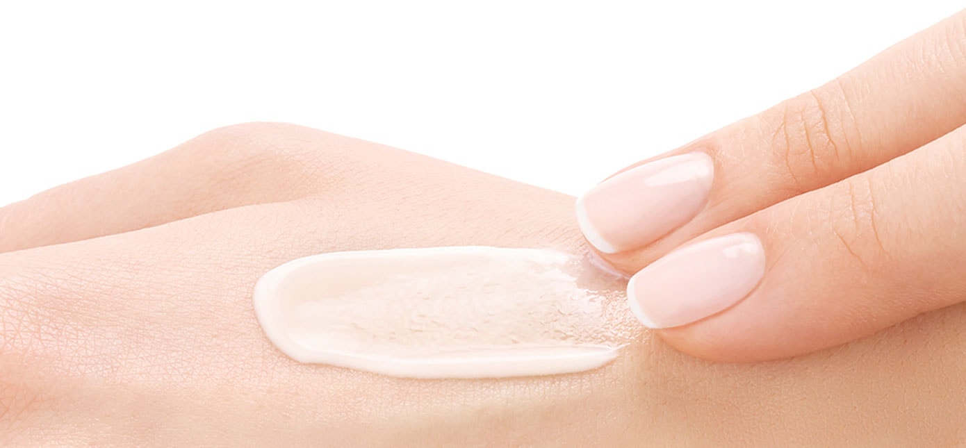 Zwei Finger verteilen Creme auf Handrücken