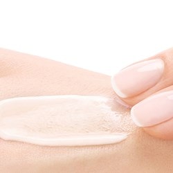 Zwei Finger verteilen Creme auf Handrücken